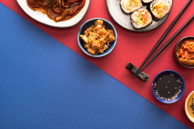 top view of bowls and plates with korean kimchi and kimbap on blue and crimson   clipart
