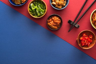 Mavi ve kırmızı renkli baharatlı Kore yemekleri olan kâselerin üst görüntüsü.  