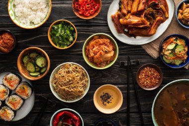 Yemek çubuklarının yanında geleneksel Kore yemekleri ve tahta yüzeyde pamuk peçete. 