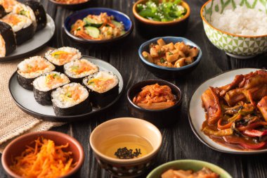 Tahta yüzeydeki lezzetli Kore yemeklerinin yanında geleneksel gimbap ve kimchi seçici odak noktası 