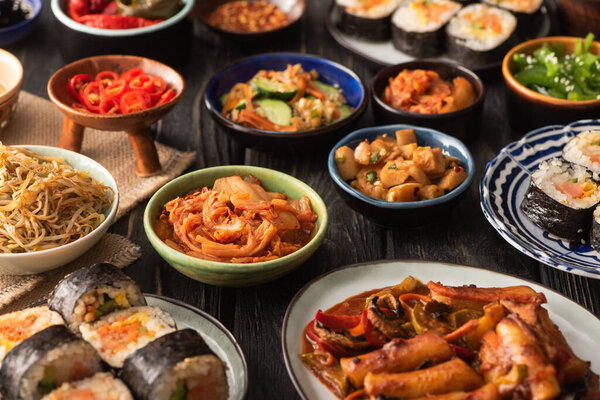 selective focus of traditional kimchi and topokki near tasty korean dishes on wooden surface 