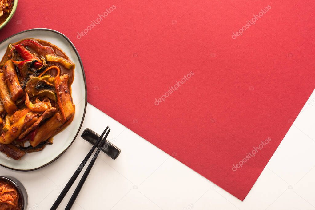 top view of chopsticks near korean topokki on white and crimson 