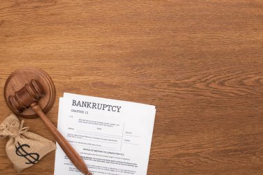 top view of bankruptcy papers, money bag and gavel on wooden background clipart