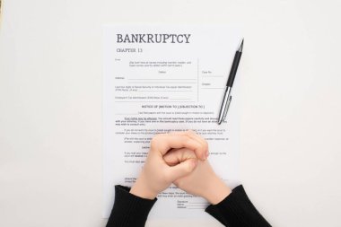 cropped view of female clenched hands on bankruptcy paper near pen on white background  clipart