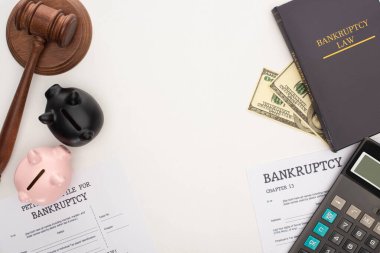 top view of bankruptcy papers and law book, gavel, piggy banks, money and calculator on white background clipart