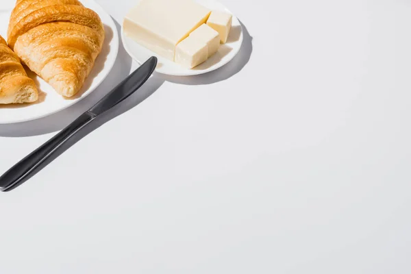Smaczne Świeże Rogaliki Pieczone Talerzu Pobliżu Masła Nożem Białym Tle — Zdjęcie stockowe