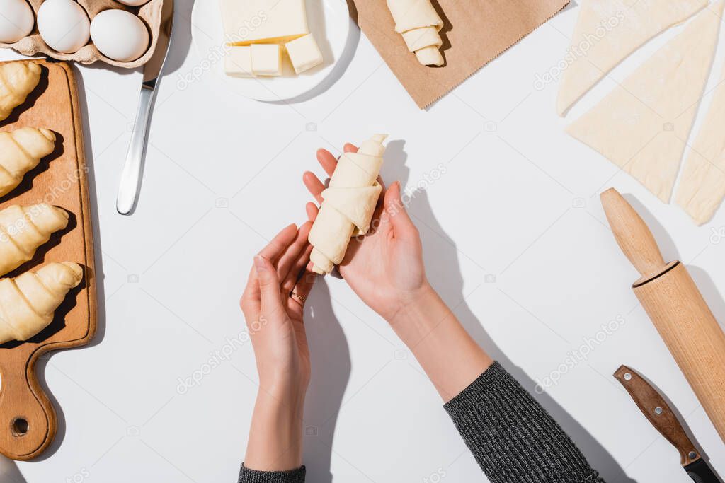 cropped view of woman making croissant on white background