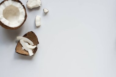 Taze hindistan cevizinin üst manzarası. Yarısı gevrek ve kabuğu beyaz arka planda.
