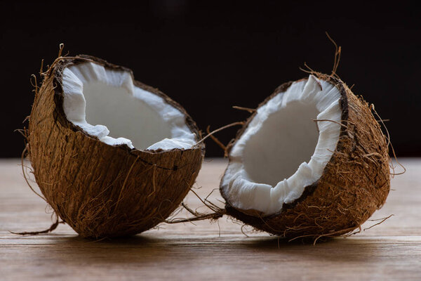 fresh tasty coconut halves on wooden table isolated on black