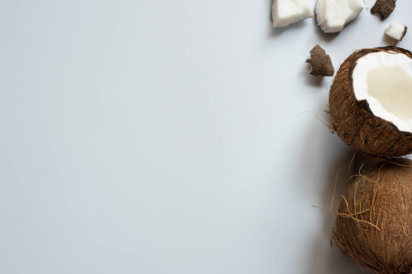 top view of whole and cracked tasty coconut half and pieces on white background