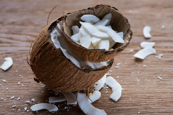 selective focus of fresh tasty coconut half and flakes in shell on wooden table