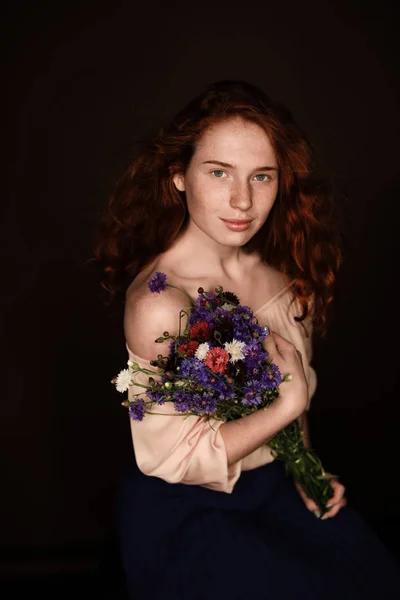 Rothaarige Mädchen mit wilden Blumen — Stockfoto