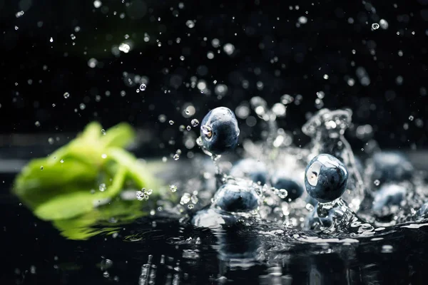 Ripe blueberries dropping in water — Stock Photo