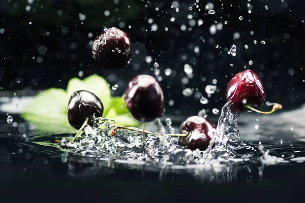 Cerises mûres tombant dans l'eau — Photo de stock