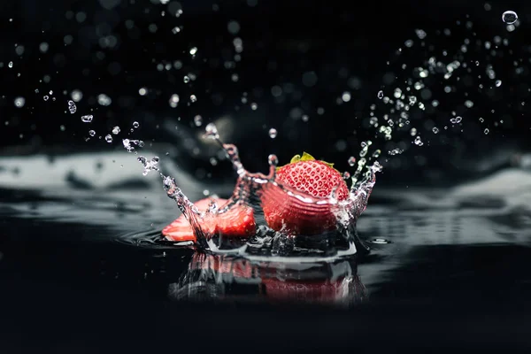 Fragole mature che cadono in acqua — Foto stock