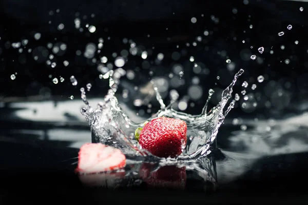 Fresas maduras que caen en el agua - foto de stock