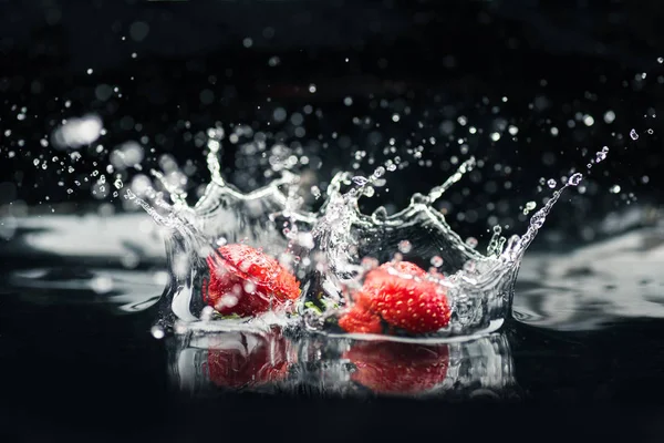 Fresas maduras que caen en el agua - foto de stock