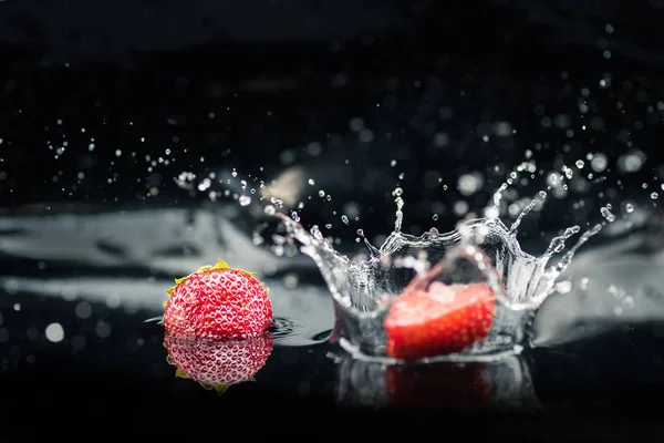 Fragole mature che cadono in acqua — Foto stock