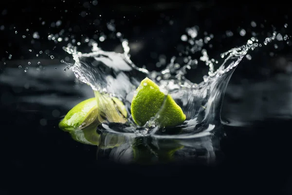 Rodajas de cal que cae en el agua - foto de stock