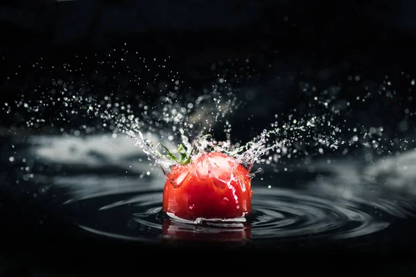 Fresh tomato falling in water — Stock Photo