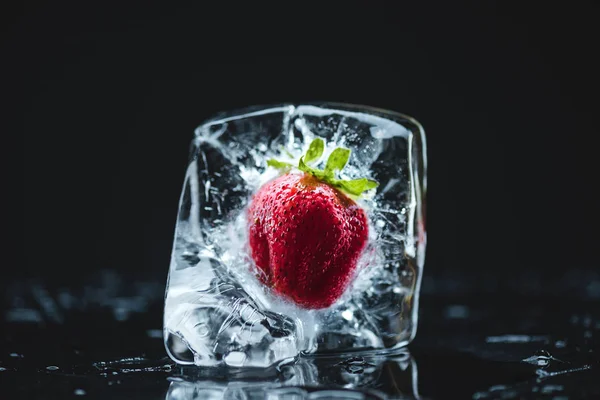 Клубника, замороженная в кубике льда — стоковое фото