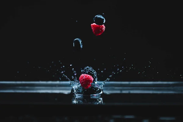 Ripe berries falling in water — Stock Photo
