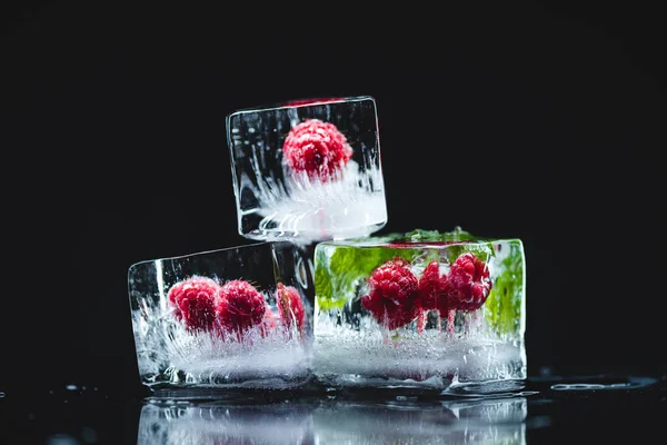 Raspberries frozen in ice cubes — Stock Photo