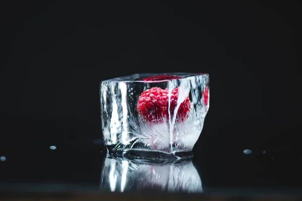 Raspberry frozen in ice cube — Stock Photo