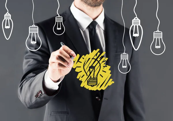 Businessman drawing light bulb — Stock Photo