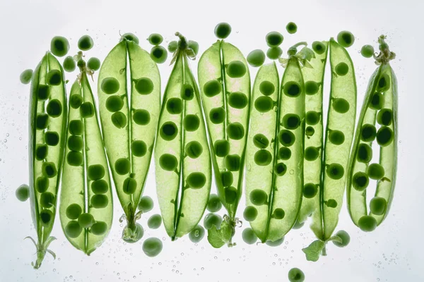 Green peas floating in water — Stock Photo
