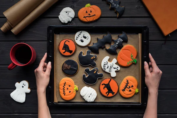 Mujer sosteniendo bandeja de galletas de halloween - foto de stock