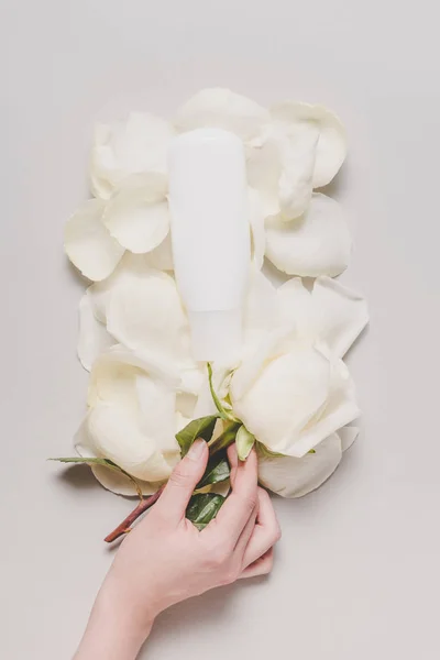 Bottle of lotion on petals — Stock Photo