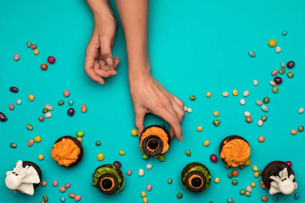 Hände und Halloween-Cupcakes — Stockfoto