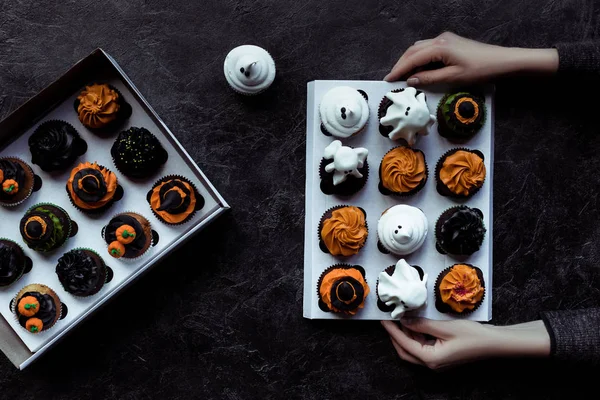 Hands holding halloween cupcakes — Stock Photo