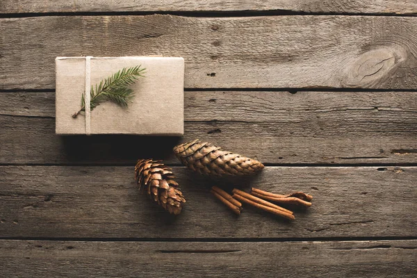 Cadeau avec cônes de pin et bâtonnets de cannelle — Photo de stock