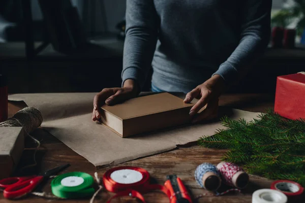 Woman wrapping book as christmas gift — Stock Photo