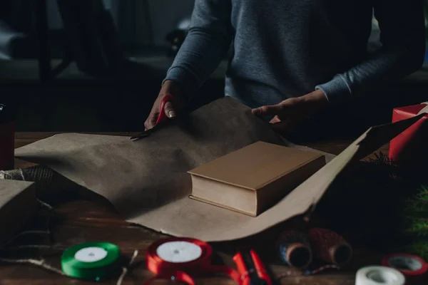 Woman wrapping book as christmas gift — Stock Photo