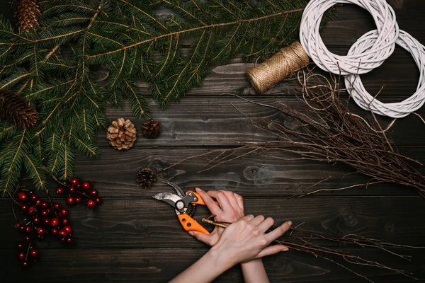 Florist making Christmas wreath with branches — Stock Photo