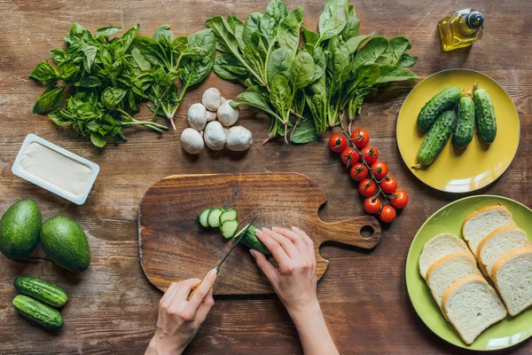 Woman cutting cucumber for breakfast — Stock Photo