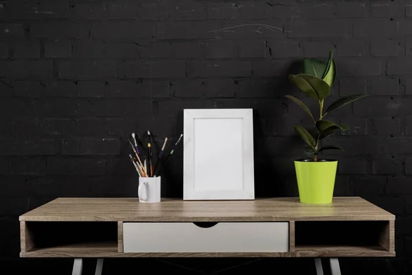 Photo frame and plant in flowerpot on table — Stock Photo