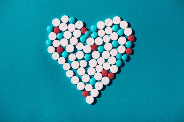 Píldoras coloridas en símbolo del corazón - foto de stock