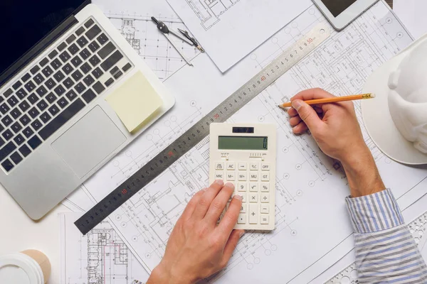 Arquitecto trabajando con planos y calculadora - foto de stock