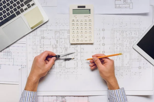 Arquitecto trabajando con planos y calculadora - foto de stock