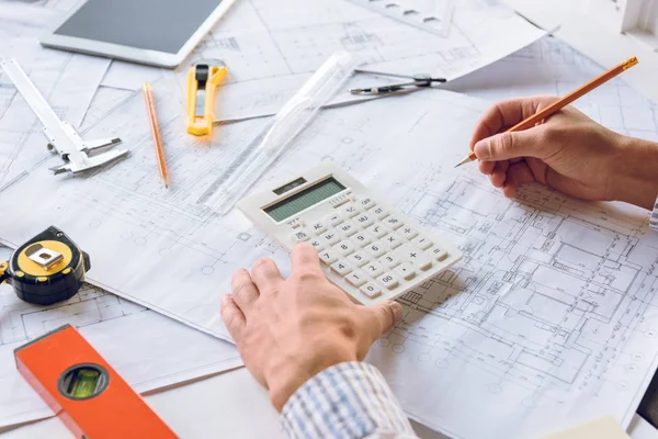 Architect working with blueprints and calculator — Stock Photo