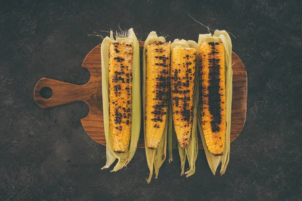 Grilled corncobs on cutting board — Stock Photo