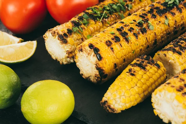 Grilled corn with limes and tomatoes — Stock Photo