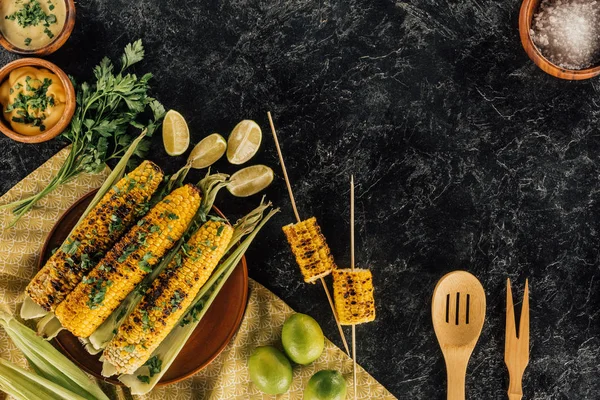 Grilled corncobs with wooden spatulas — Stock Photo