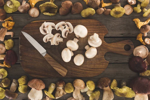 Planche à découper avec couteau et champignons coupés — Photo de stock