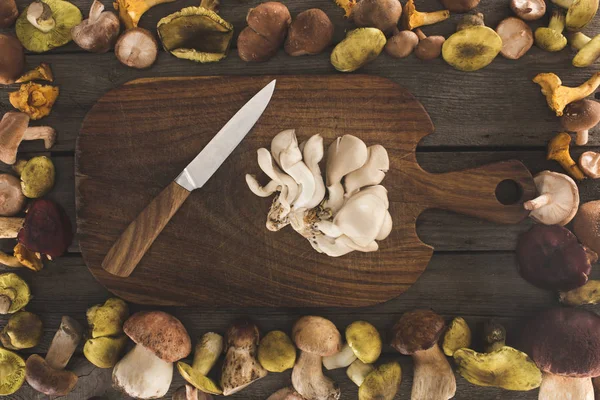 Cogumelos de ostra e faca na tábua de corte — Fotografia de Stock