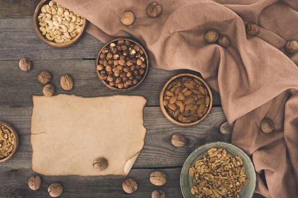 Nuts in bowls and parchment — Stock Photo